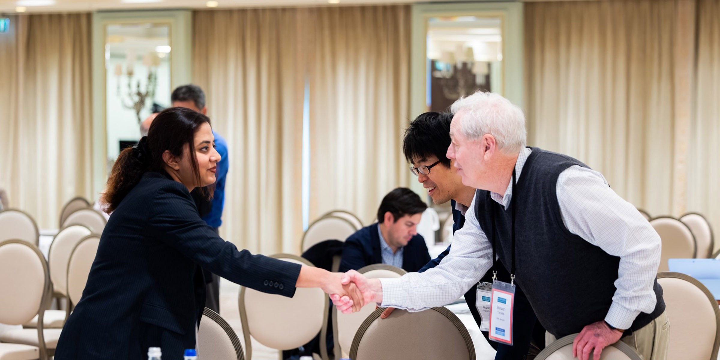 Three business people meeting and shaking hands in a conference room