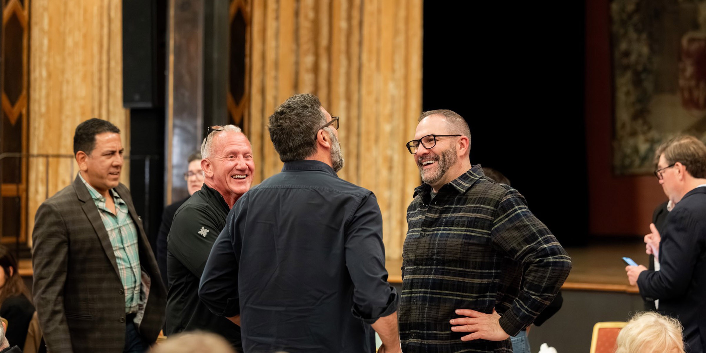 a group of businessman laughing at a conference in a grand setting