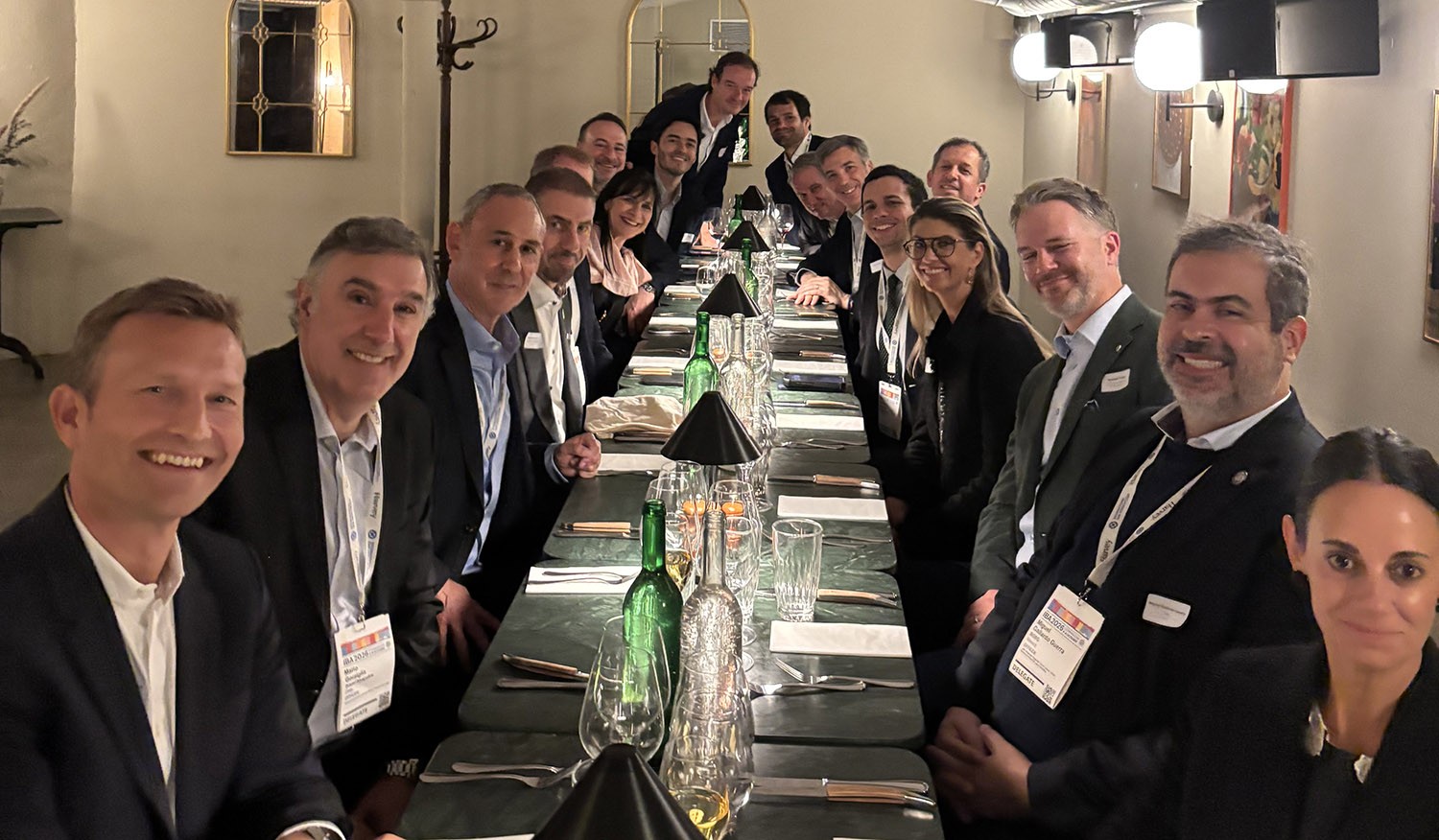 Group of business people around a long dining table in the evening.